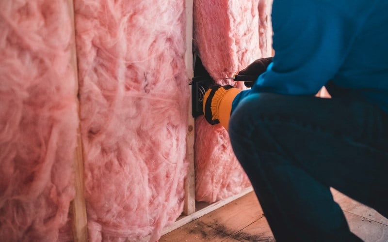 pink insulation being installed by an installer dressed blue