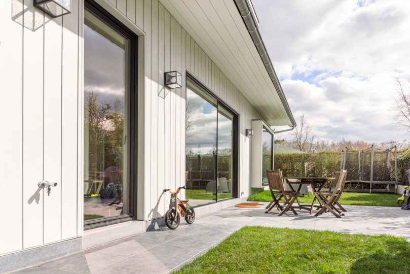 Witte Cedral gevelbekleding op een modern huis met grote glazen deuren en een buitenterras